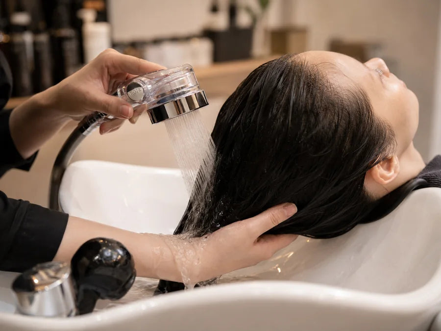 Stylist rinsing a client's hair with Supercharge Pro in a salon basin